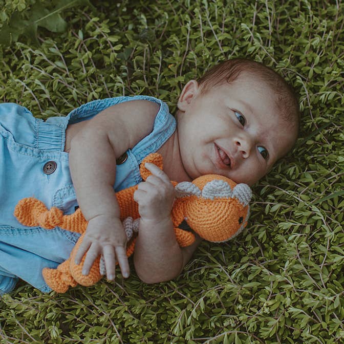 Baby organic dino lovey worn and cuddled lifestyle view