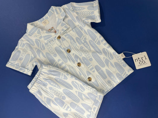 Children's outfit with shirt and shorts on a blue background, featuring a pattern of fruits and vegetables.