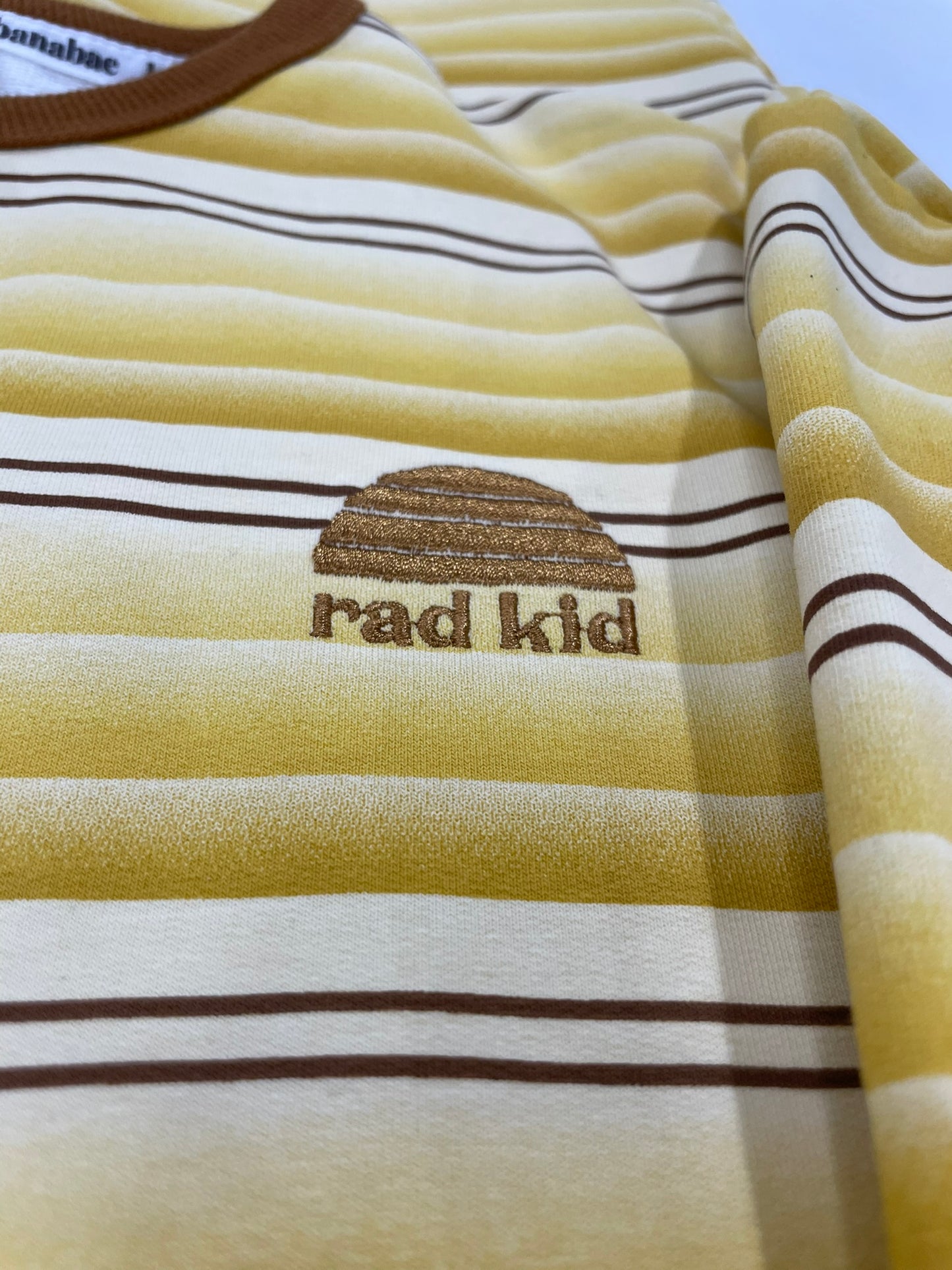 Striped shirt with 'rad kid' text and logo on a plain background