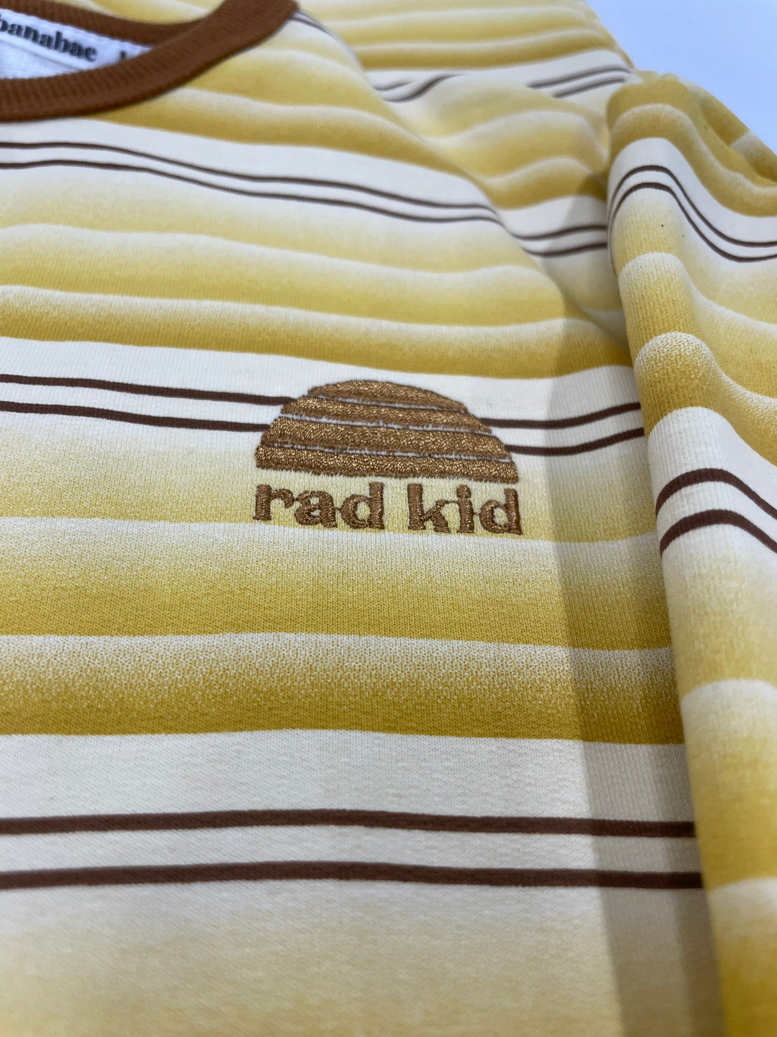 Striped shirt with 'rad kid' text and logo on a plain background
