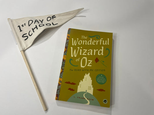 Book titled 'The Wonderful Wizard of Oz' with a small flag reading '1st Day of School' on a white background