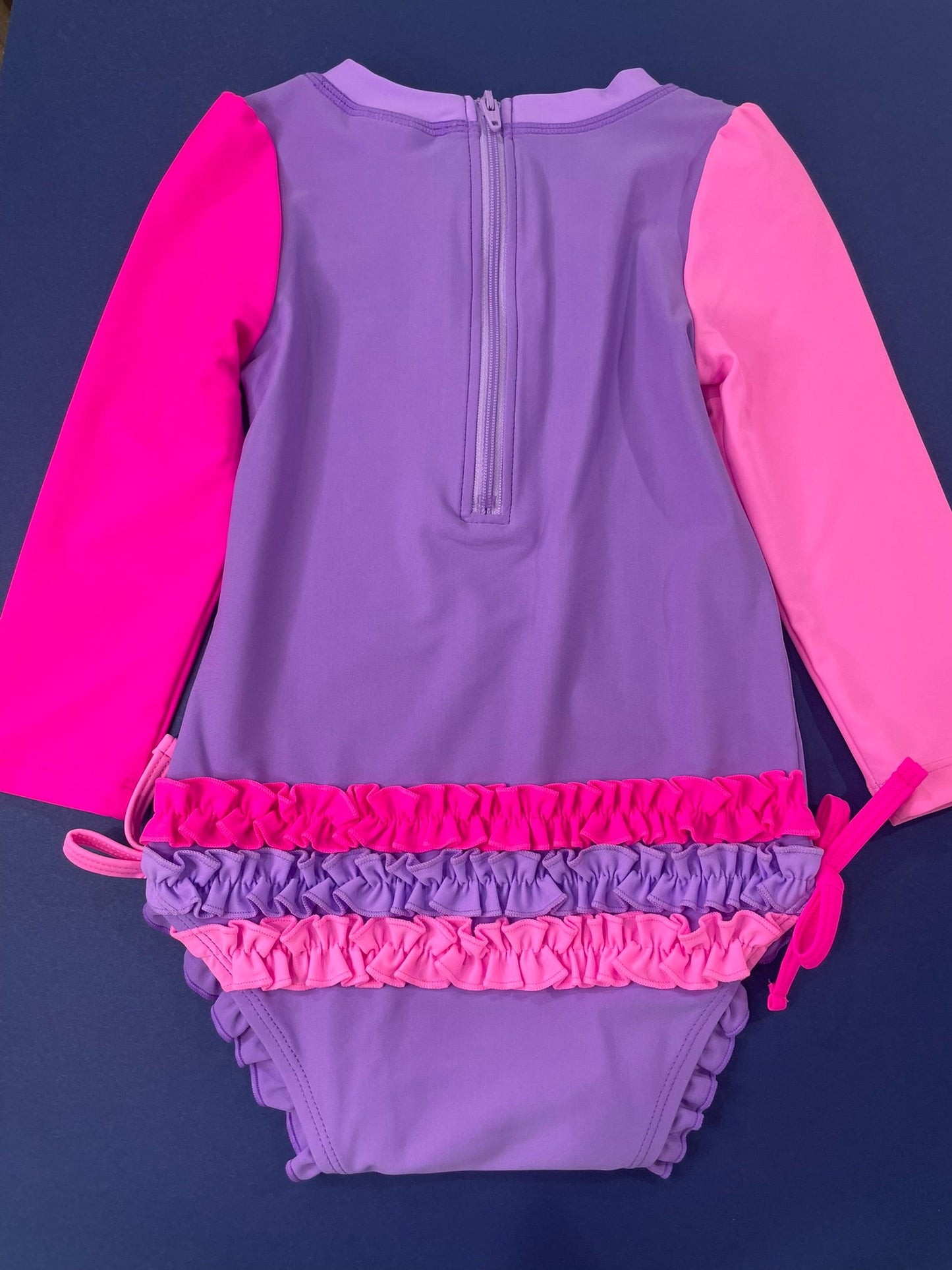 Purple swimsuit with pink trim on a dark blue background
