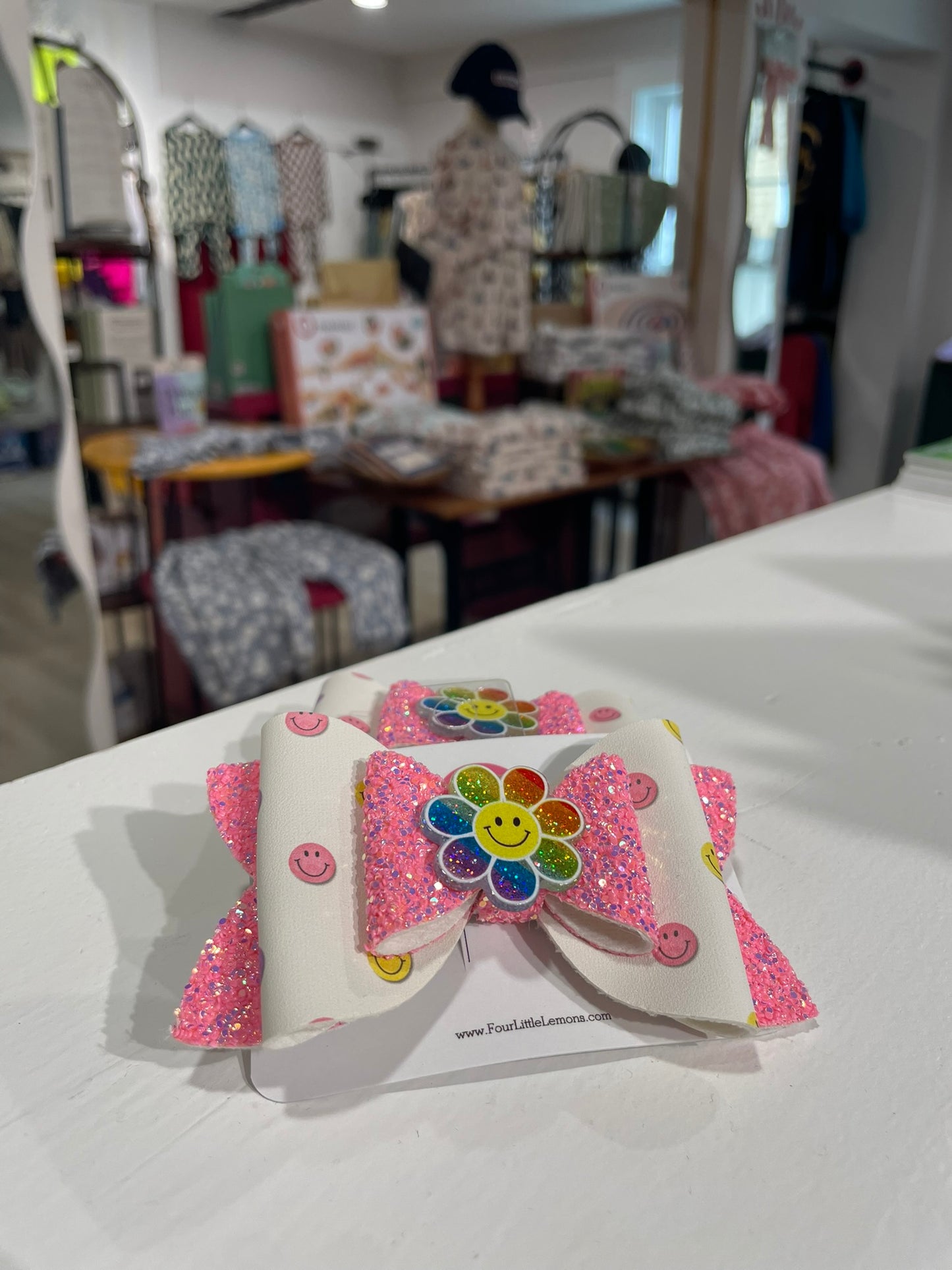 Colorful hair bow with a flower design on a white surface in a store setting.